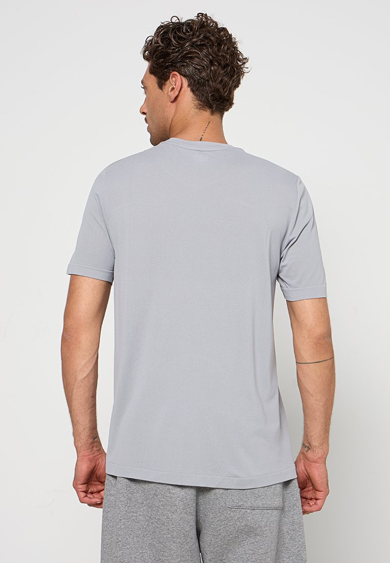 Šedé tričko s krátkými rukávy, kulatý výstřih, strukturovaná tkanina, rovný střih, jednobarevný design, na zadní straně žádné viditelné vzory nebo grafika.