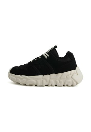 Black low-top sneaker with white chunky sole featuring embossed text, white laces, and mesh fabric details.