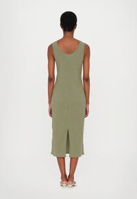 Rochie midi ribbed de culoare verde măsliniu, cu spate decupat, design ajustat și detaliu cu fante în spate, realizată dintr-un material tricotat. Siluetă simplă și elegantă.