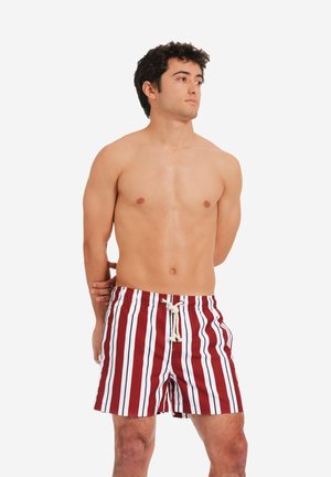 Costume da bagno a righe rosse e bianche con vita elastica e cordoncino, caratterizzato da una vestibilità ampia e un tessuto morbido e leggero.