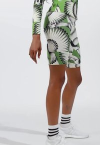 Green patterned cycling shorts featuring a design of black and white feathers. The material appears stretchy, with a fitted design and seamless finish.