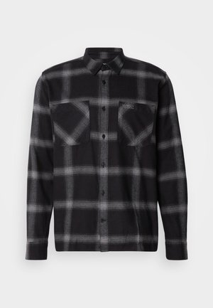 Black and grey plaid flannel shirt with long sleeves, button-up front, two chest pockets, and a subtle logo on the left pocket.