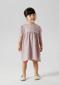 Robe en coton lilas avec des manches courtes bouffantes et une silouhette évasée, ornée de petits motifs floraux violets.