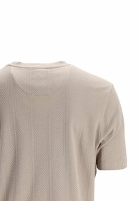 T-shirt beige à manches courtes avec un motif chevron texturé et un col arrondi ; fabriqué en tissu léger et respirant.