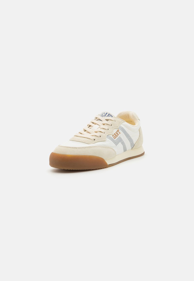 Retro-Sneaker aus creme- und weißem Stoff mit grauen Streifen, Wildlederakzenten und einer Sohle aus Gummi. Schnürsenkel und Zunge in passender Farbe.