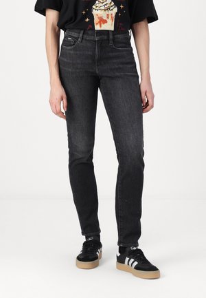 Black skinny jeans with a faded finish, featuring a standard waistband, five-pocket design, and subtle stitching details.