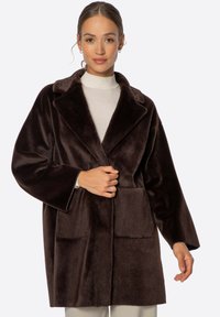 Abrigo de pelo sintético marrón con cuello de muesca, dos bolsillos frontales y mangas sueltas. Textura suave; diseño de longitud media.