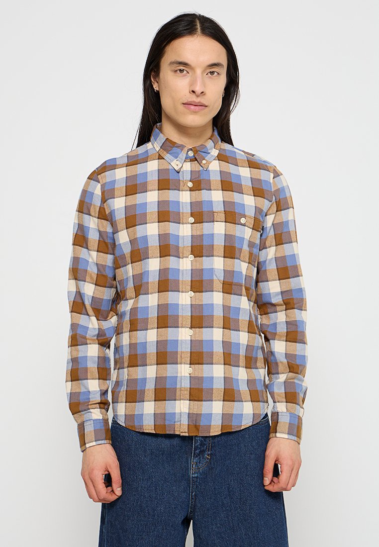 Camicia a quadri marrone e blu con colletto, maniche lunghe e tasca sul petto. Realizzata in tessuto intrecciato con una consistenza morbida.