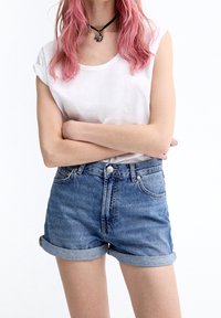 White cotton t-shirt paired with blue denim shorts with rolled cuffs, featuring a button closure and front pockets. Simple and classic design.