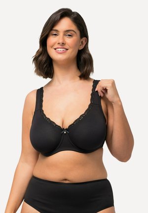 Schwarzer kabelloser BH mit einem Spitze-gesäumten Ausschnitt, verstellbaren Trägern und einem kleinen Schleifenakzent in der Mitte. Glattes Material und volle Abdeckung.