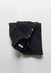 Chaqueta de mezclilla negra con cierre de botones en el frente, dos bolsillos en el pecho, textura suave y mangas dobladas, situada sobre una superficie plana.
