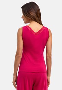 Fuksjowy top bez rękawów z dekoltem w kształcie litery V zdobionym koronką, wykonany z miękkiego materiału, pokazany od tyłu, w komplecie z dopasowanymi spodniami.