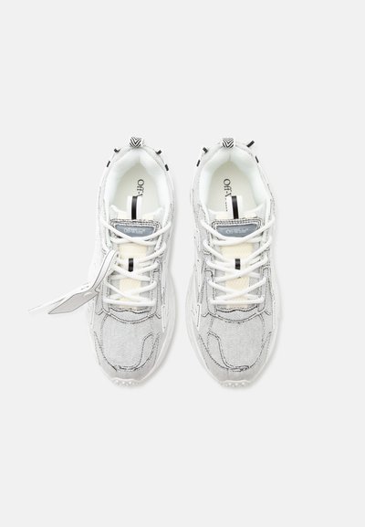 Ζευγάρι λευκά sneakers Off-White με μαύρα ράμματα, χοντρές σόλες, κορδόνια και επώνυμα ταμπελάκια, εμφανιζόμενα από πάνω σε απλό φόντο.