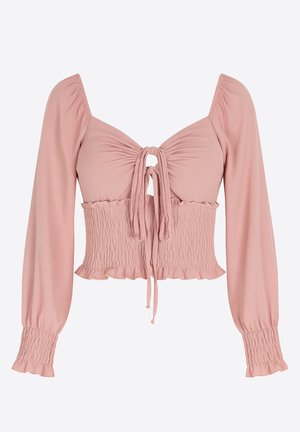 Haut court rose pâle avec manches longues, corsage smocké et détail noué à l'avant. Tissu doux avec ourlet volanté et accents aux poignets.