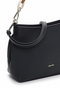 Sac à main en cuir noir à forme souple, surface texturée, bandoulière réglable et accent décoratif en chaîne. Présente un logo doré.