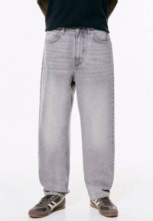 Helle graue Jeans aus Denim mit einer lockeren, geraden Passform. Verfügt über ein klassisches Fünf-Taschen-Design und dezente Ausbleichungen. Kombiniert mit grauen Sneakers.