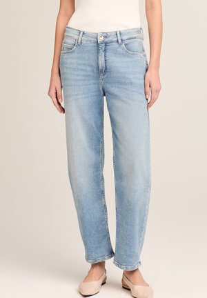 Hellblaue Jeans mit geradem Bein, kombiniert mit beigen Slingback-Ballerinas und einem weißen ärmellosen Oberteil, gezeigt von der Mitte des Oberkörpers bis zu den Füßen.