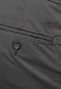 Svarta tygbyxor med en framficka och knäppning. Har diskret logobroderi och en jämn textur.