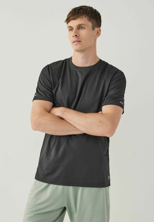 Tricou sportiv scurt din material ușor, respirabil, care absoarbe umezeala. Are guler rotund și un branding subtil pe mânecă.