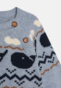 Pull en tricot bleu clair avec des motifs de baleine et de zigzag. Présente des boutons en bois brun et un col côtelé. Texture douce.