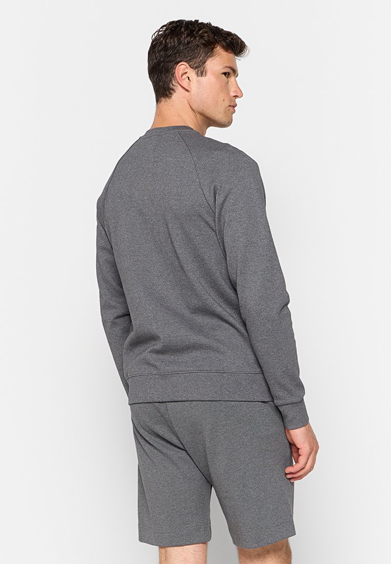 Sudadera gris con cuello redondo y dobladillo acanalado, hecha de una tela suave, combinada con pantalones cortos gris a juego, presenta un ajuste relajado.