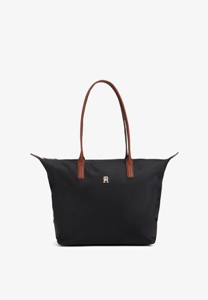 Fekete nagy táska barna bőr fogantyúkkal és egy kis arany "TH" logóval a középen elöl, fehér háttér előtt bemutatva.