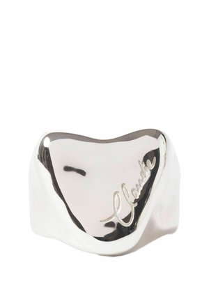 Anneau en argent lisse et brillant avec une forme arrondie irrégulière et une gravure cursive sur sa surface.