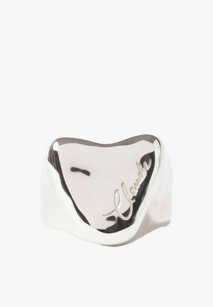 Anneau en argent lisse et brillant avec une forme arrondie irrégulière et une gravure cursive sur sa surface.