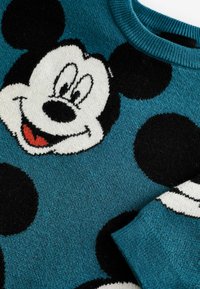 Pull teal con grande grafica di Topolino in bianco e nero, lavorazione a maglia testurizzata e pois neri. Collo e polsini a coste.