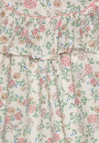 Tessuto stampato con fiori nei toni di rosa, beige e blu su uno sfondo crema. Bordo arricciato lungo il collo con un dettaglio a bottone.