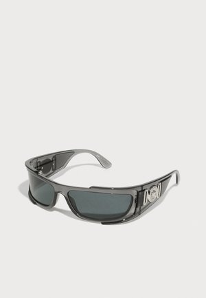 Saulesbrilles ar pelēku plastmasas rāmi, tumšiem lēcu tonējumajiem stikliem un sudraba dekoratīvajiem elementiem uz kājiņām. Elegants, apliecinošs dizains.
