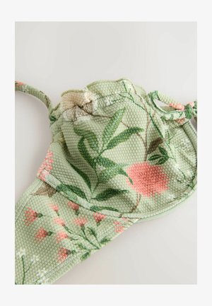 Grüne Gesichtsmaske mit Blumenmuster aus strukturiertem Stoff, verziert mit rosa und weißen Blüten, verstellbaren Ohrschlaufen und konturierter Form.