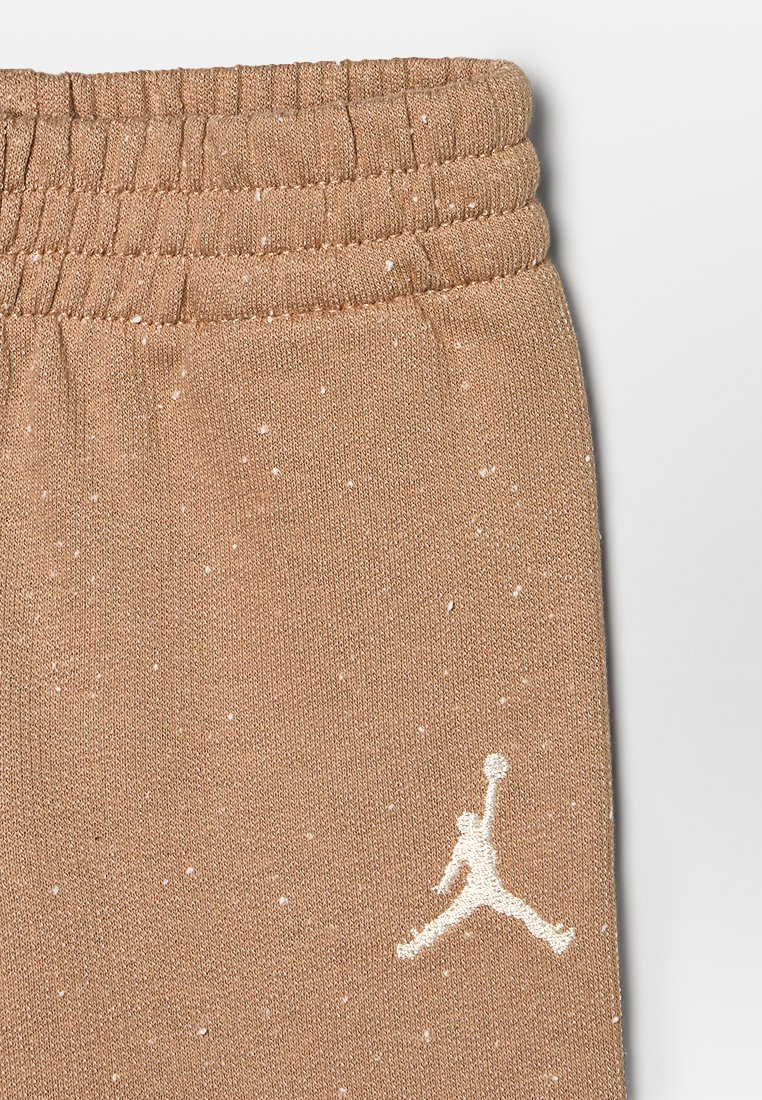 Pantalones de chándal marrones con un acabado texturizado, que presentan una cinturilla acanalada y motas blancas. Incluye un logo Jumpman blanco en contraste.