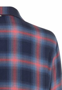 Navy plaid shirt featuring red and blue check patterns, a classic collar, and textured fabric with subtle stitching details.