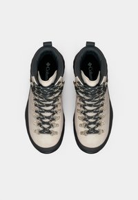 Botas de caminhada bege claras com um colarinho cinza, ganchos de metal e atacadores texturizados. Sola de borracha para tração e interior almofadado.