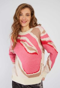 Pull en tricot présentant des motifs abstraits roses et beiges, encolure ronde et poignets côtelés. Matériau doux avec une finition légèrement texturée.