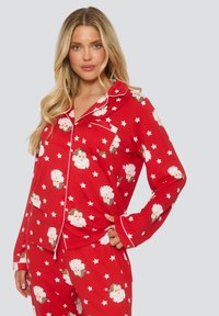 Rote Schlafanzüge mit einem wiederholten Muster von Cartoon-Weihnachtsmann-Gesichtern und Sternen, mit weißen Paspeln entlang des Kragens und der Ärmel.