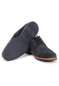 Chaussures en daim bleu marine avec une finition lisse, bout rond, semelle plate et bords de semelle en brun contrasté. Comprend des lacets foncés et des accents texturés.