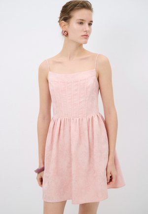 Abito rosa chiaro con corpetto aderente, spalline sottili e gonna arricciata. Presenta una texture floreale e una lucentezza sottile su tutto il tessuto.
