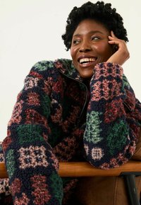 Fleecejacke mit einem mehrfarbigen Patchworkdesign in Grün, Pink und Marineblau; mit Reißverschluss und hohem Kragen; weicher Stoff.