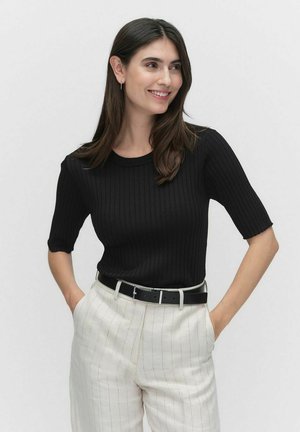 Black ribbed short-sleeve top with a crew neck, worn with light-colored striped trousers and a black belt. Smooth texture, fitted design.