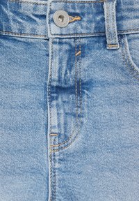 Los jeans de mezclilla azul claro presentan un diseño clásico de cinco bolsillos, con costuras naranjas y un cierre de botón de metal en la cintura.