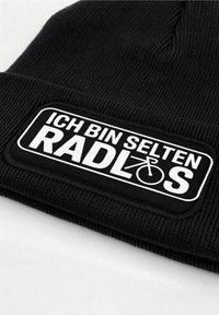 Black knitted beanie with a rectangular white patch featuring text "ICH BIN SELTEN RADLØS" and a bicycle icon. Text prominently displayed.