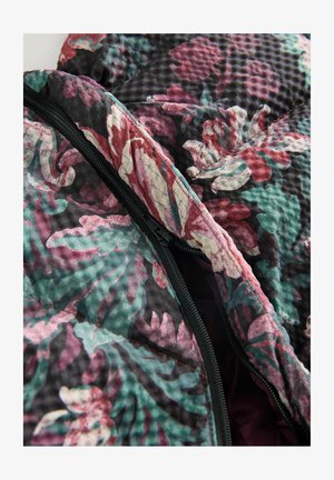 Floral-patterned quilted fabric jacket in dark colors. Features a black zipper and soft lining. Textured surface with varying hues of green, pink, and red.