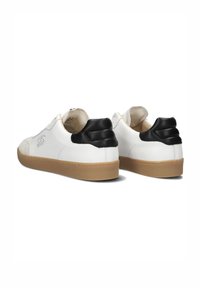 Baskets en cuir blanc avec des accents en daim noir au talon, design low-top, semelle en caoutchouc texturé, et détails de couture minimalistes.