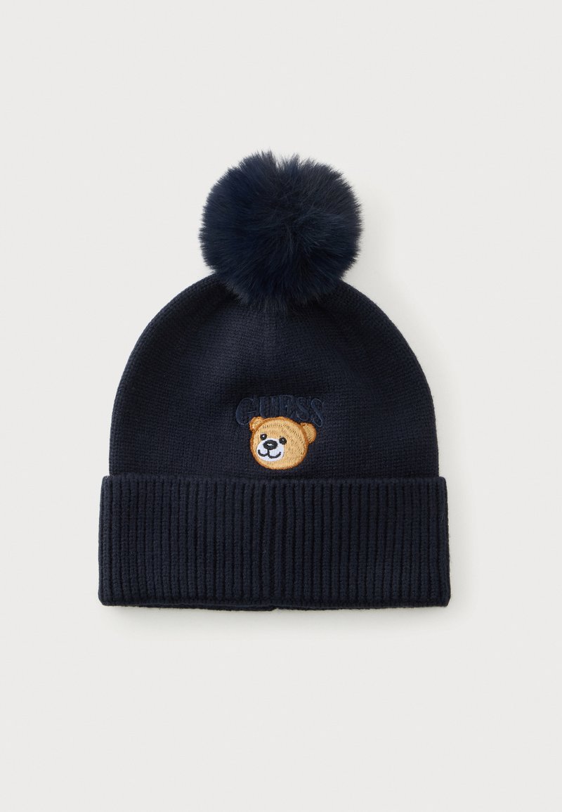 Dark navy knit beanie with a large pom-pom, ribbed cuff, and a small embroidered smiling bear face on the front.