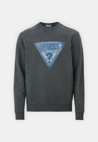Sudadera gris con puños y dobladillo acanalados, que presenta un gran logo triangular bordado en azul con el texto "GUESS" y acentos decorativos.