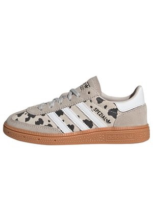 Sneaker beige Adidas Spezial con strisce bianche, motivo maculato nero, suola in gomma e lacci grigi.