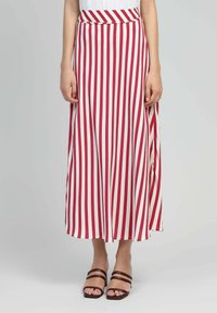 Jupe longue en A avec des rayures verticales rouges et blanches. Fabriquée en tissu léger, elle présente une taille haute et une fente pour un mouvement confortable.