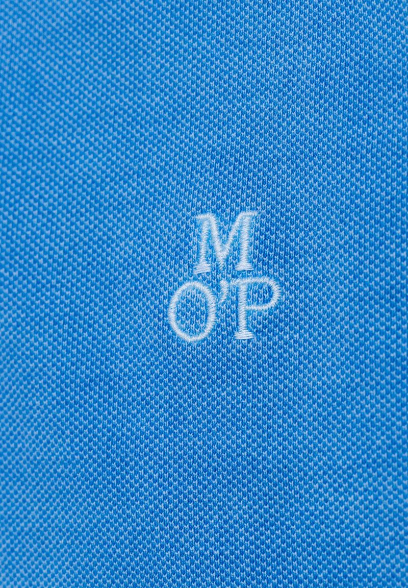Texturiert blauer Stoff mit gestickten Buchstaben "MOP" in Weiß, zentral auf dem Material platziert.
